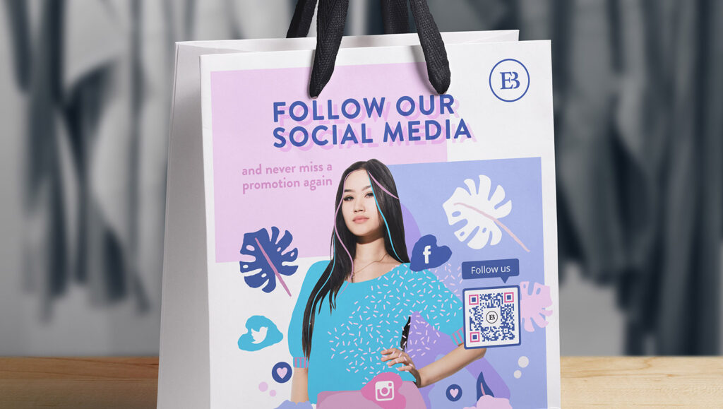 A boutique's shopping bag with a Social Media QR Code on it prompting customers to scan and follow their socials