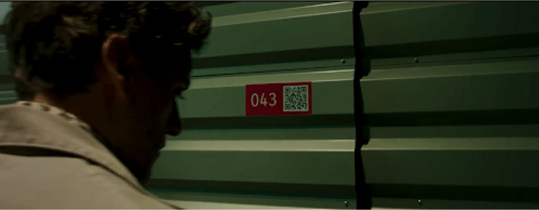 Steven Grant stands in front of storage locker 043 next to a QR Code.